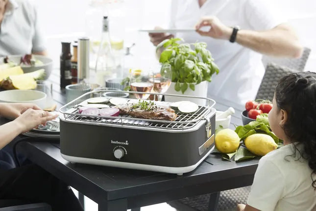 Elektrische tafelgrill op tafel met grillrooster en donkergrijze behuizing