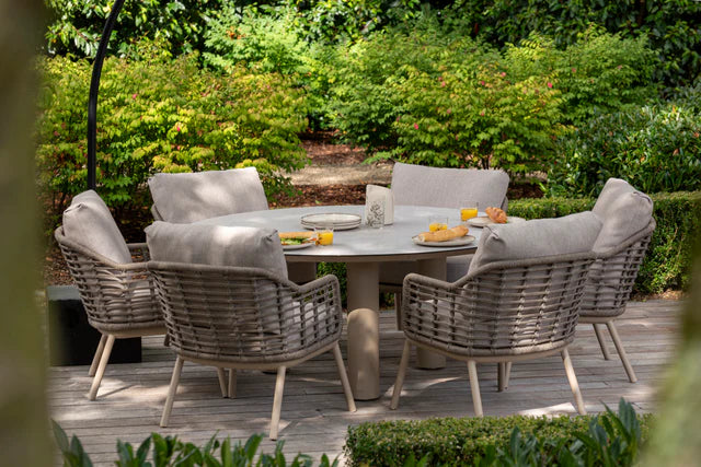 Tuindiningset met ronde tafel en grijze gevlochten stoelen met beige kussens