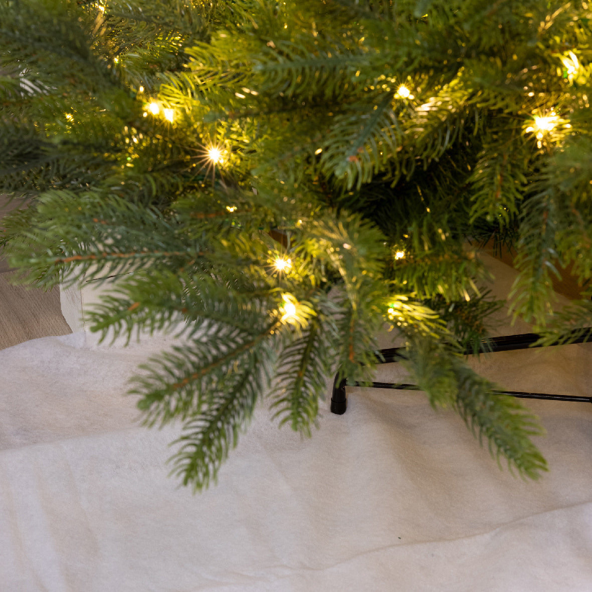 Sneeuwdeken van polyester onder een kerstboom, licht witte stof