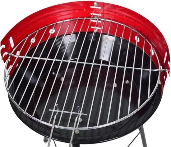 Ronde rode houtskoolbarbecue met grillrooster boven de zwarte vuurkom