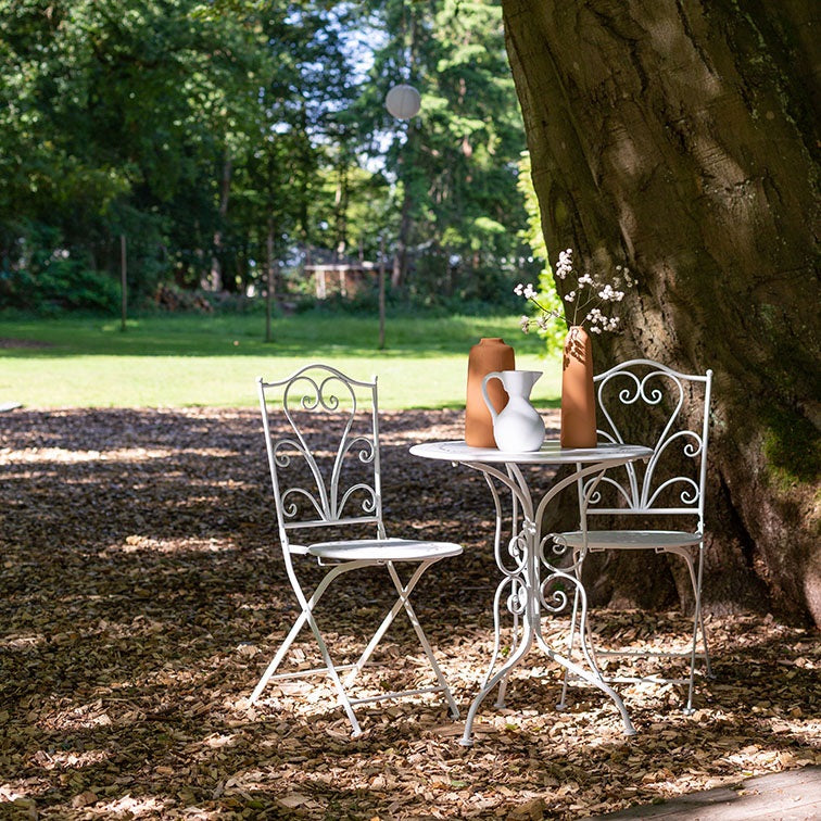 Witte metalen bistroset met ronde tafel en twee stoelen naast elkaar