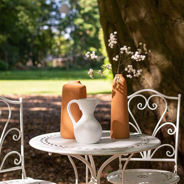 Witte metalen bistroset met ronde tafel en twee stoelen, sierlijke krullen