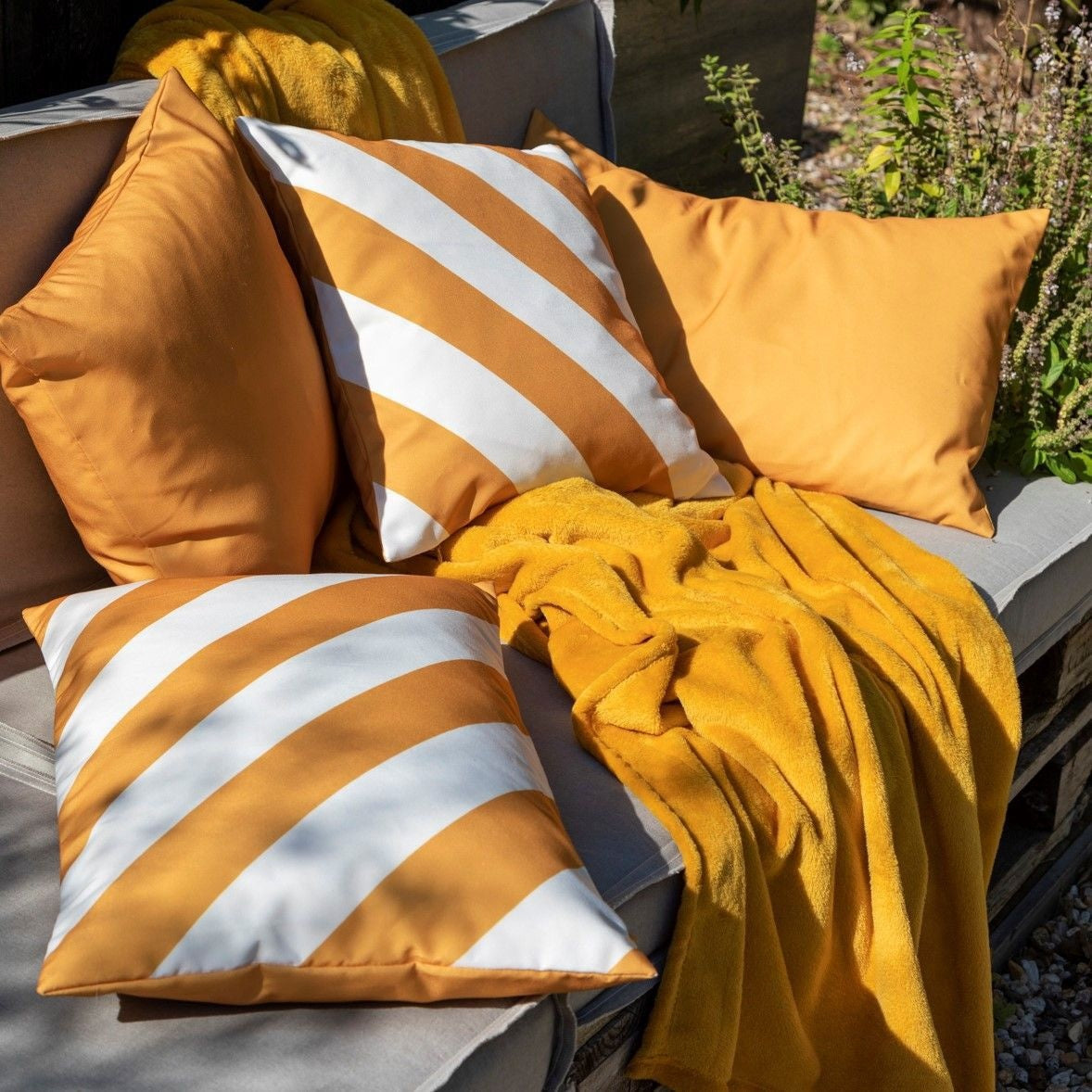 Outdoor sierkussen met oranje-witte diagonale strepen op bank