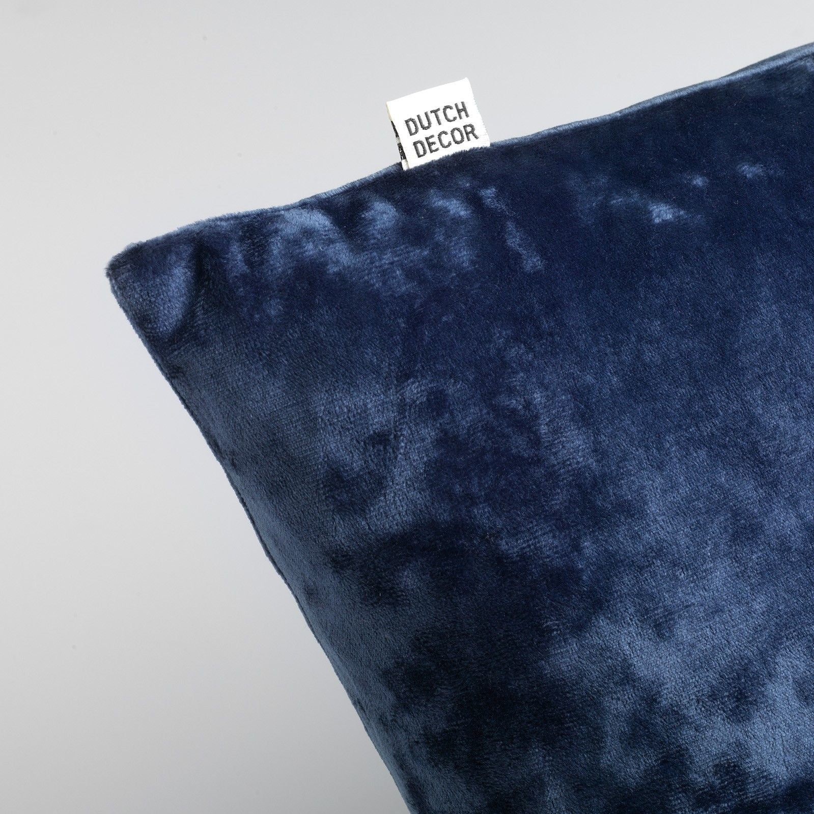 Blauw fluwelen sierkussen met hoekdetail en merklabel DUTCH DECOR