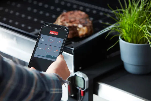 Digitale barbecuethermometer met app, zwart display en hand die scherm bedient