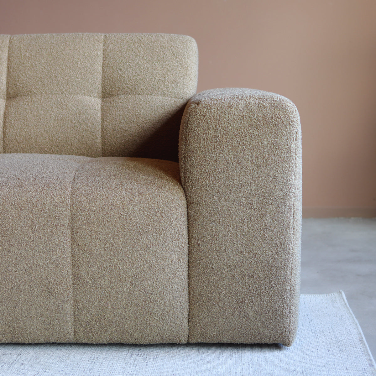 Beige gestoffeerde hoekbank met armleuning en afgeronde zit, close-up