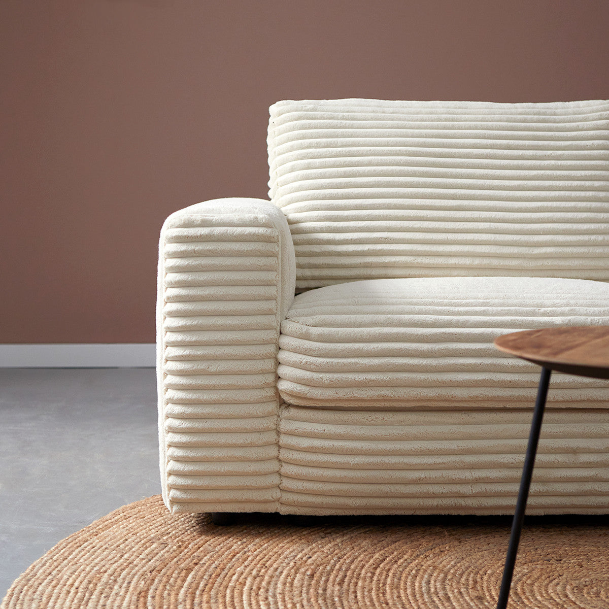 Crème chaise longue rechts met geribde bekleding en dikke zitrugkussens.