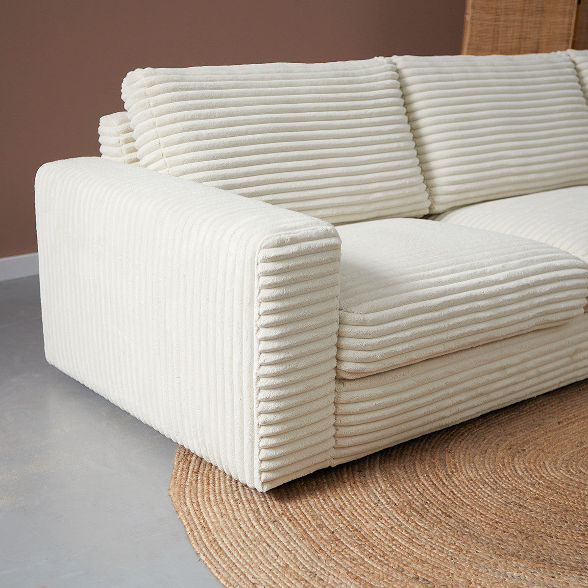 Crème hoekbank met chaise longue rechts, lage pootjes en blokvormige zit.