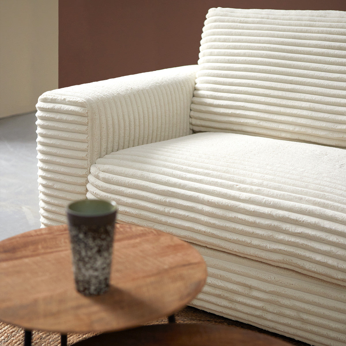 Crème hoekbank met chaise longue rechts en ronde armleuning, met gestreepte bekleding.