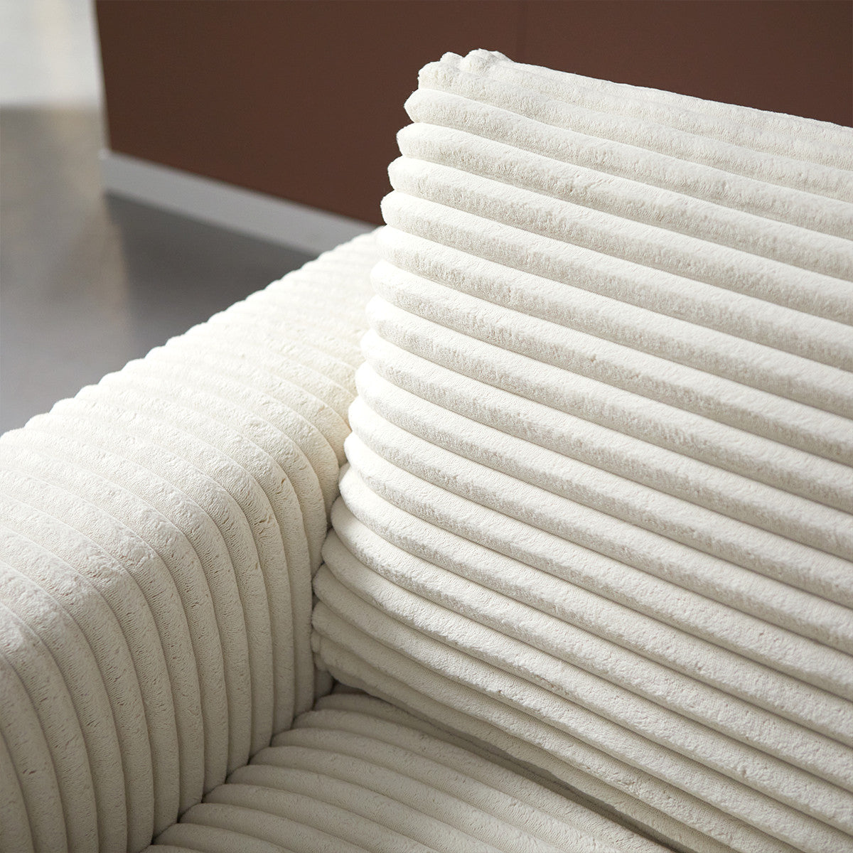 Hoekdetail van crème bank met geribde rug en zijkussen op chaise longue.