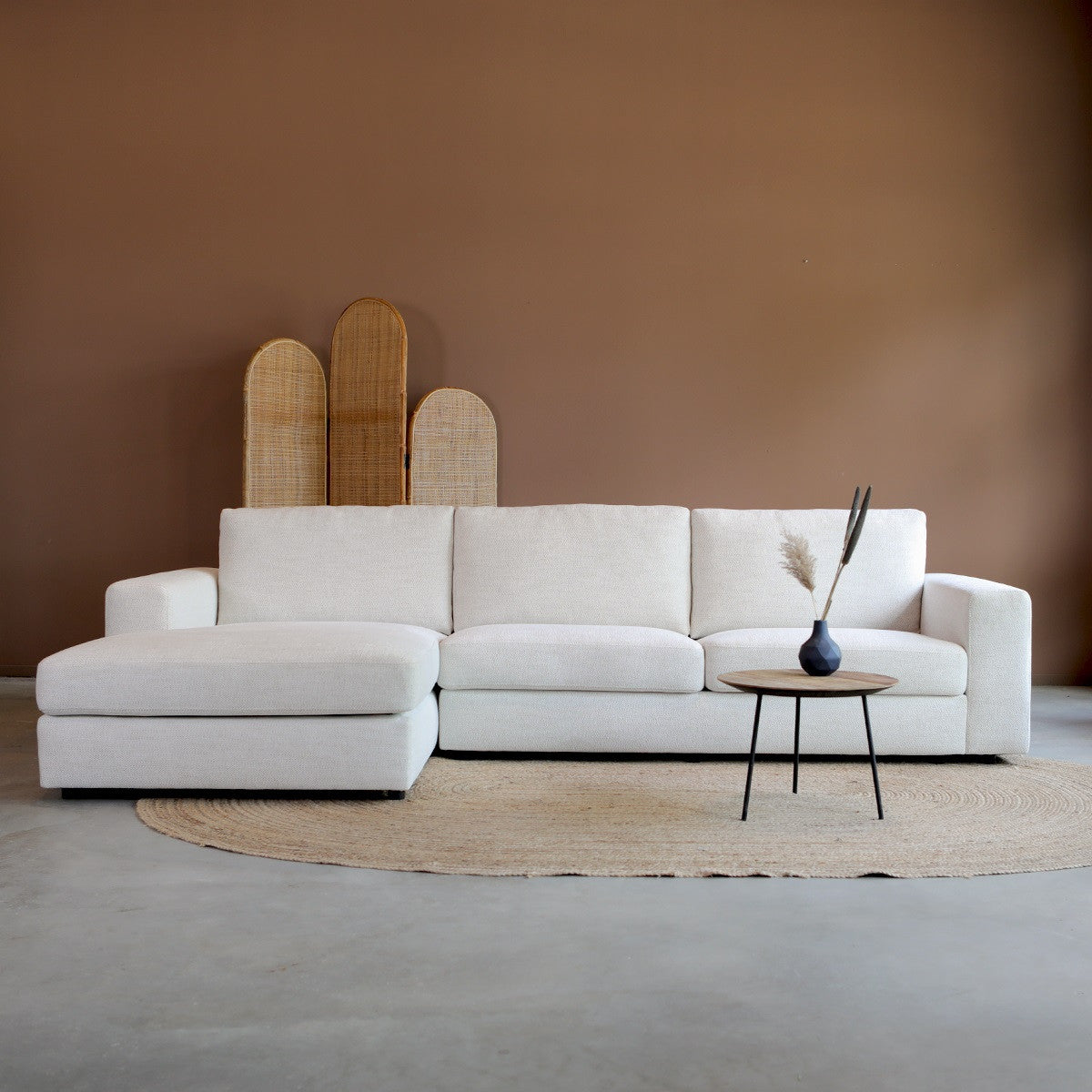 Lichtbeige stoffen bank met chaise longue links en losse kussens