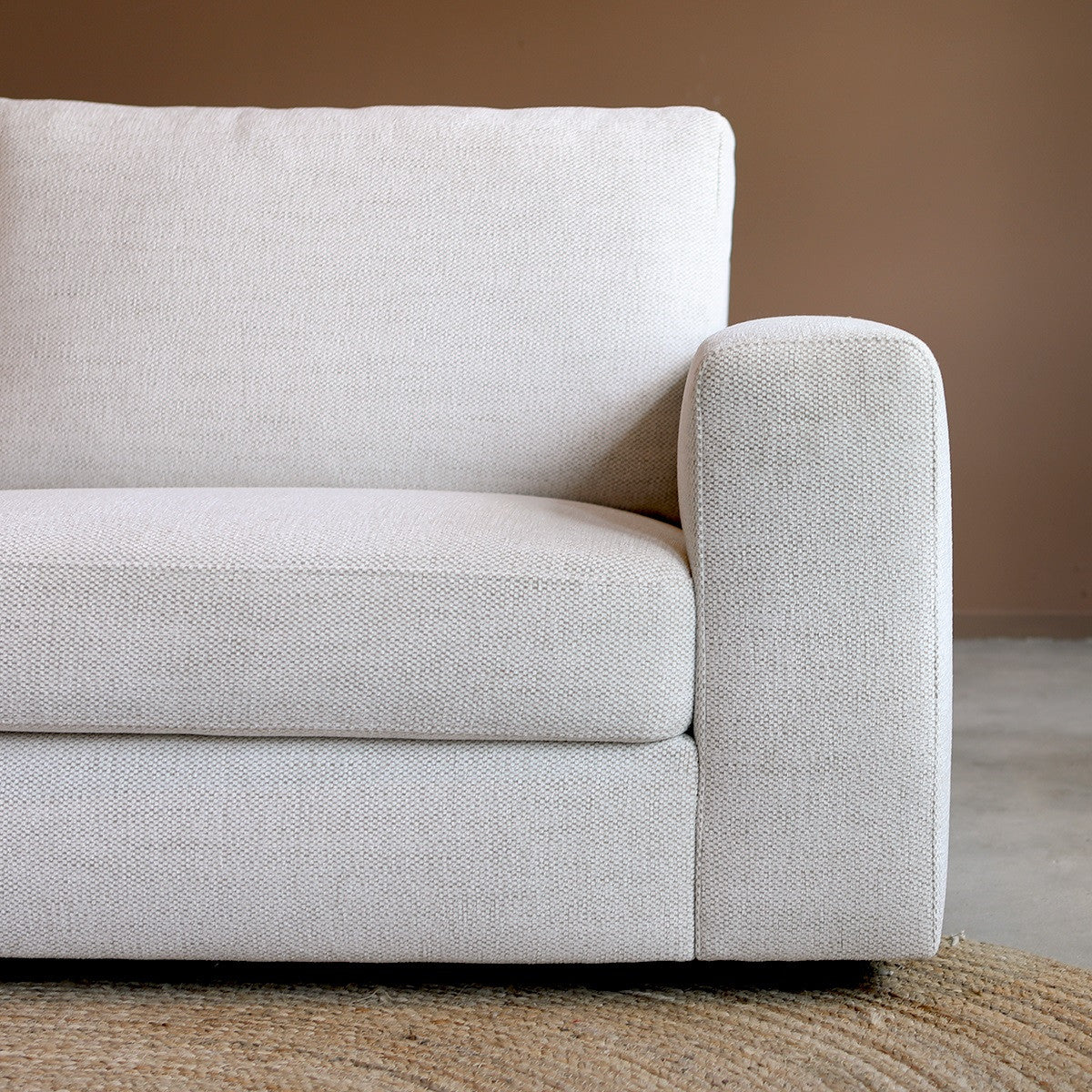 Lichtbeige bankzitting met hoge, afgeronde armleuning en textielstof
