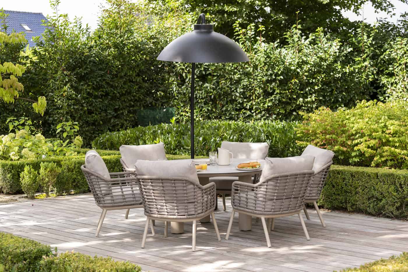 Tuin eethoek met meerdere lage diningstoelen, grijsbruin vlechtwerk en beige kussens