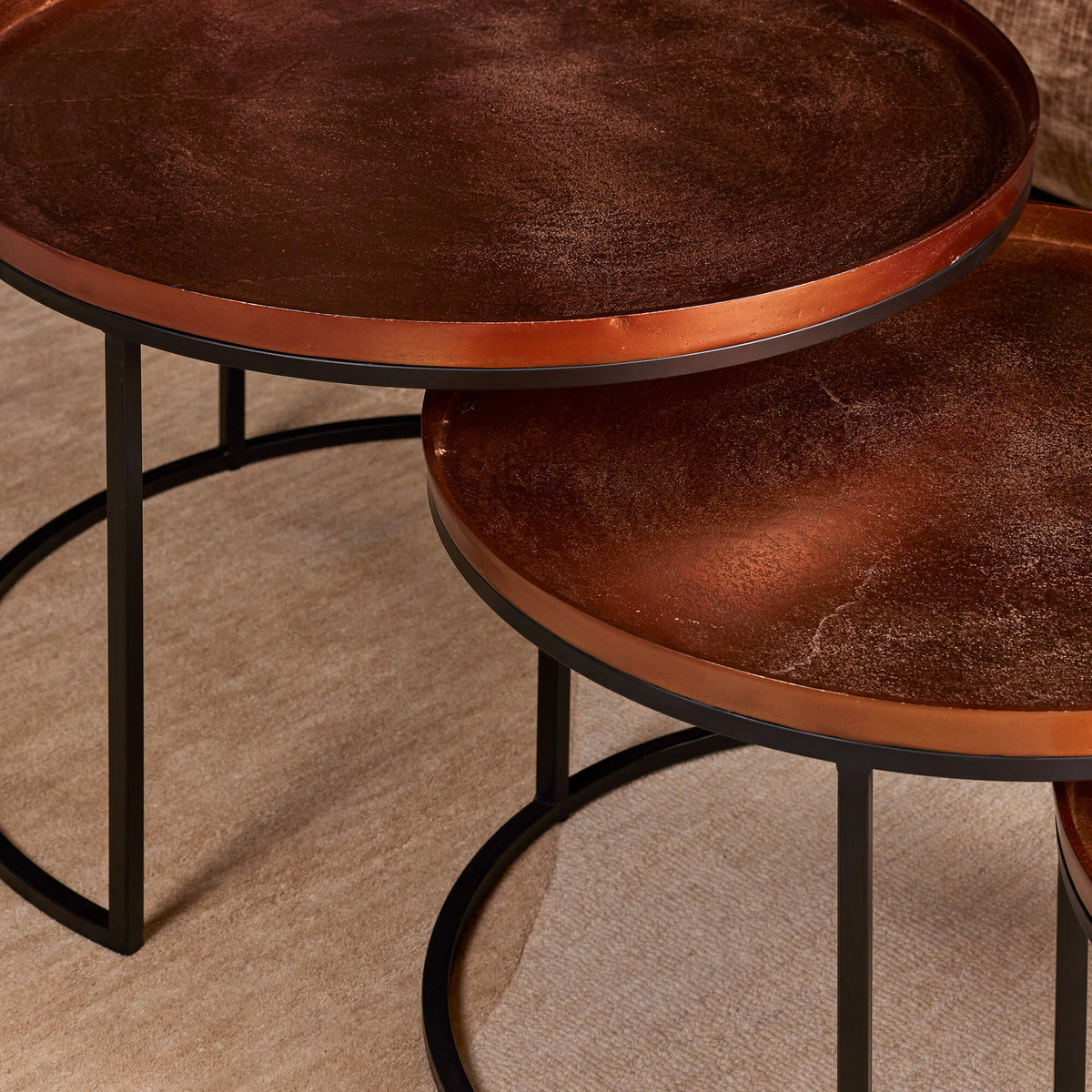 Ronde salontafelbladen met bruin houtnerf en zwarte metalen poten, close-up