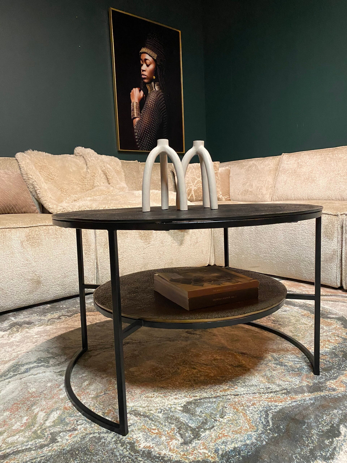 Zwarte ronde salontafel met drie witte beugels en metalen frame, onderplank zichtbaar
