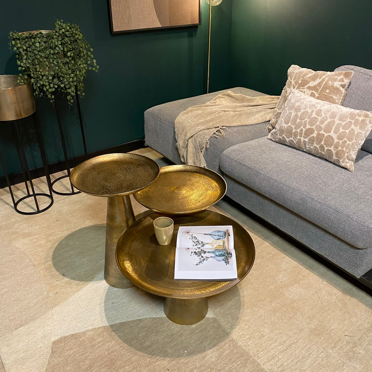 Gouden ronde salontafelset met drie bladen, mok en tijdschrift op de bovenste tafel