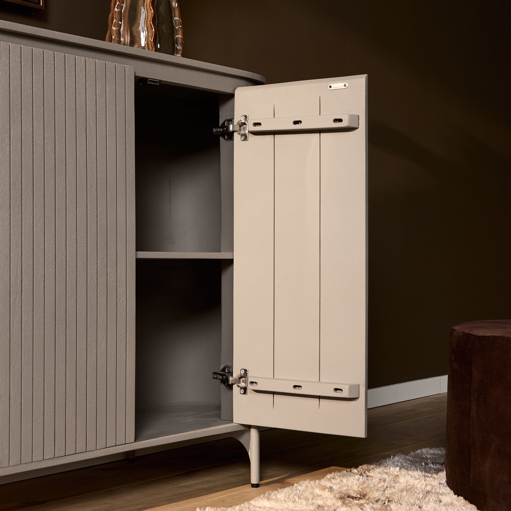 Taupe kast met open scharnierdeur en zichtbare plankruimte, verticaal gestreept front.