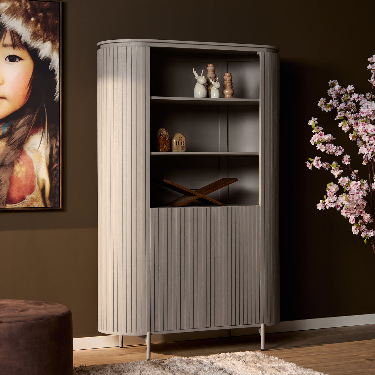 Taupe wandkast met open legplanken en geribd front, afgeronde bovenkant.