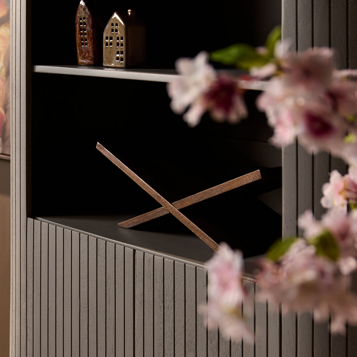 Taupe wandkast met legplanken en kruisvormige steun in de open kast.