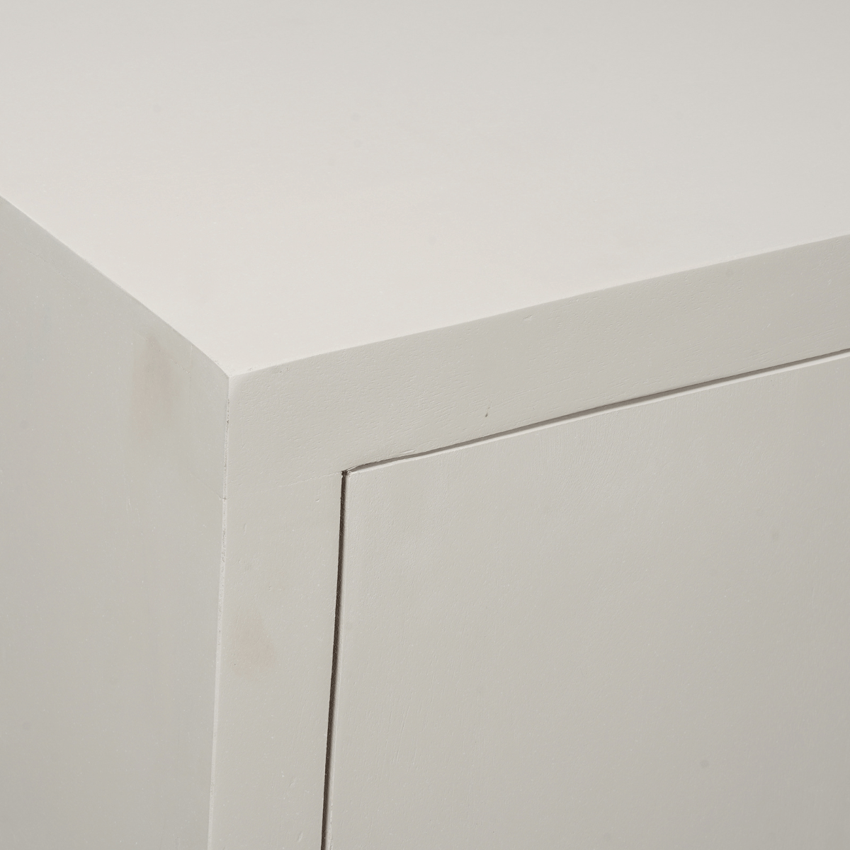 Dressoir-detail van hoek en deurpaneel, strakke lijnvoering en lichtgekleurde afwerking.