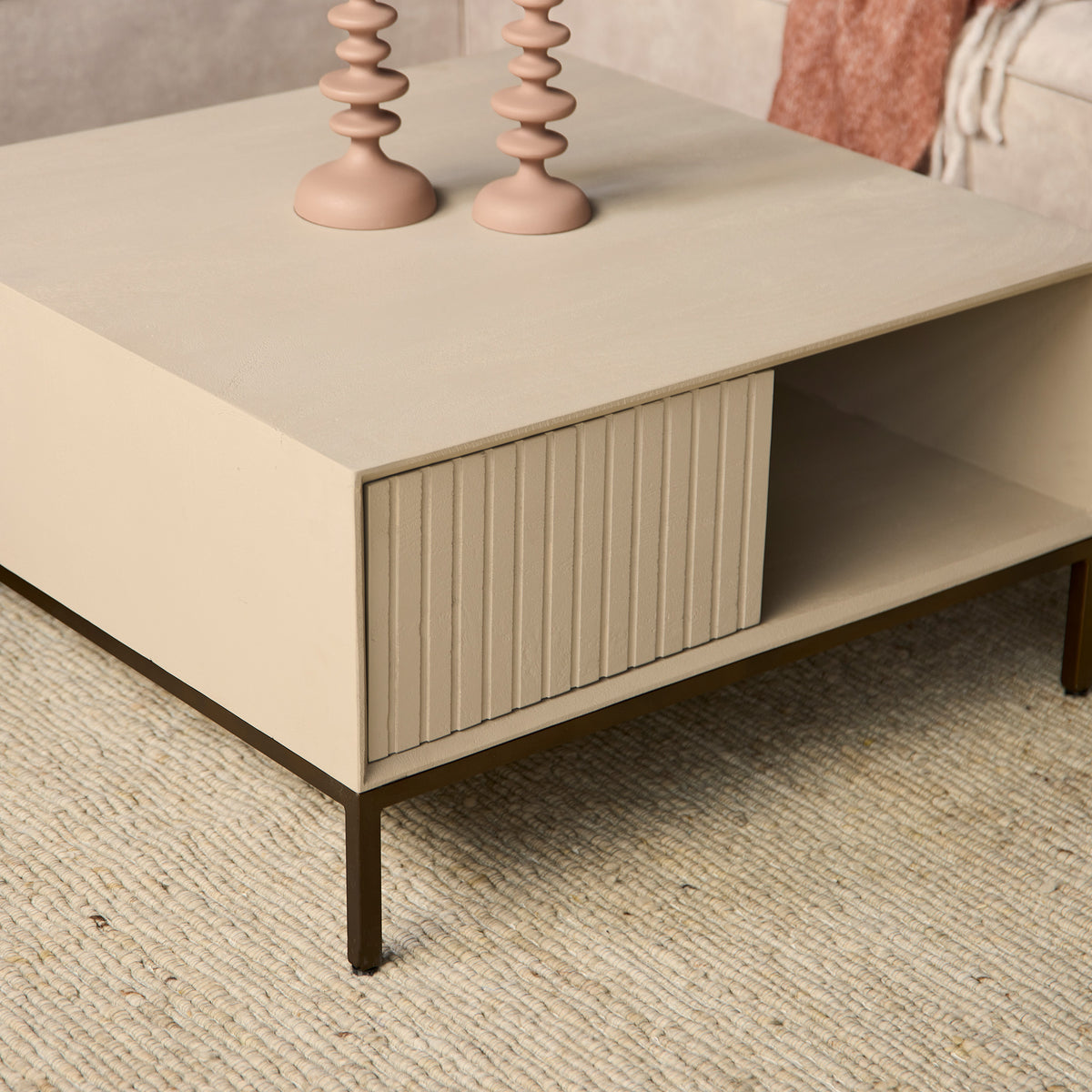 Vierkante salontafel zandkleur met open opbergvak en frontpaneel met verticale ribbels.