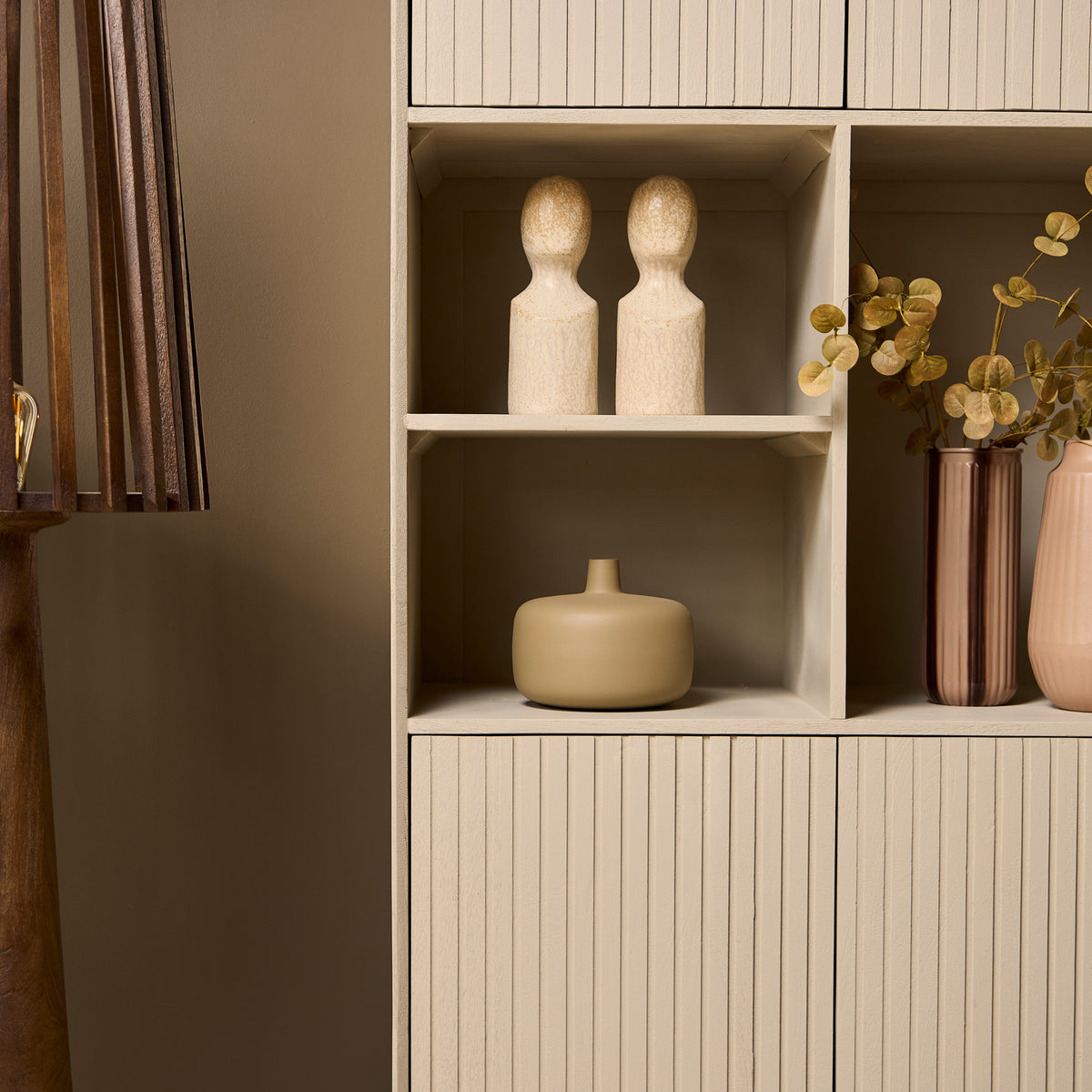 Zandkleurige vakkenkast met open schappen en twee onderdeuren met ribbelmotief
