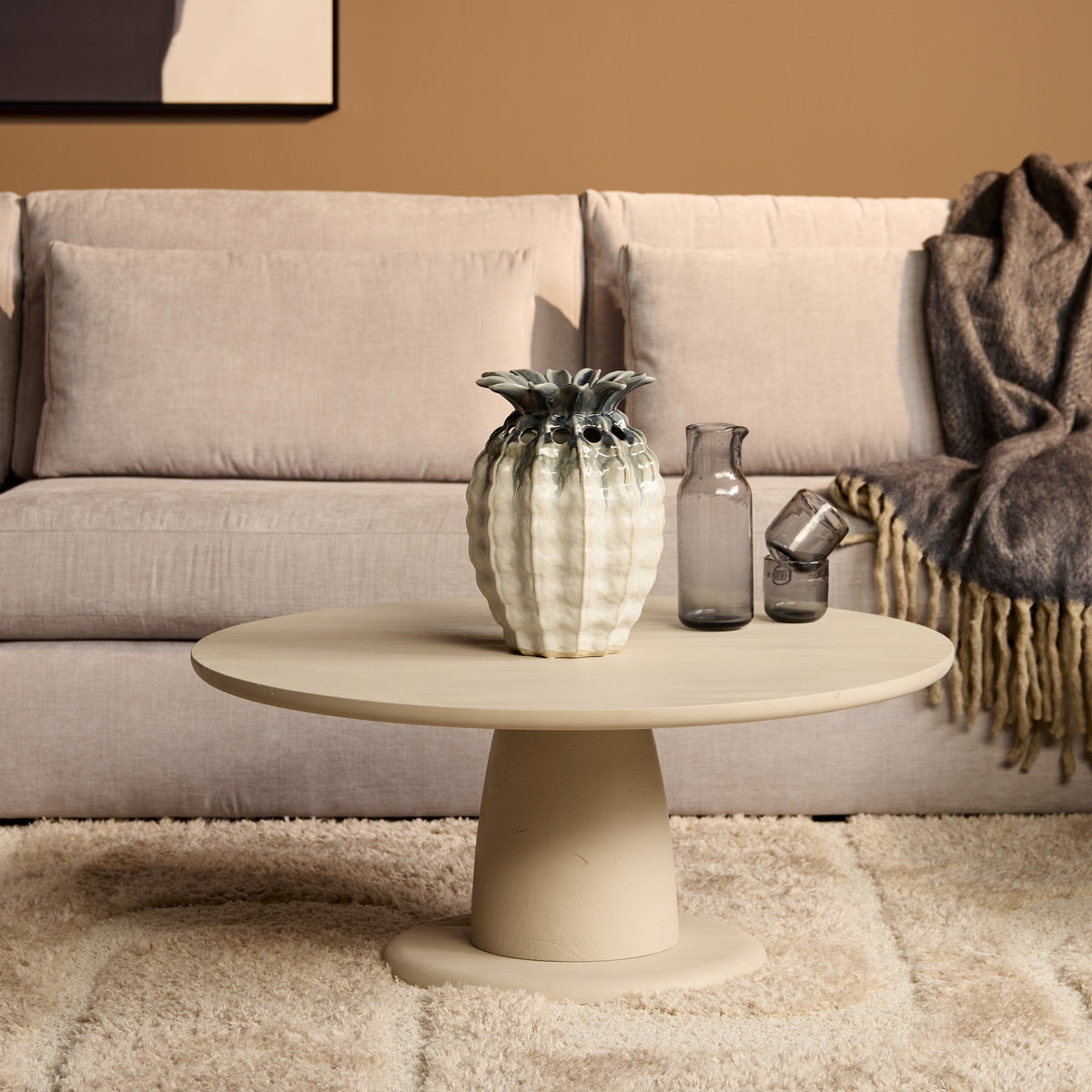 Ronde salontafel met lichtkleurig blad en centrale poot