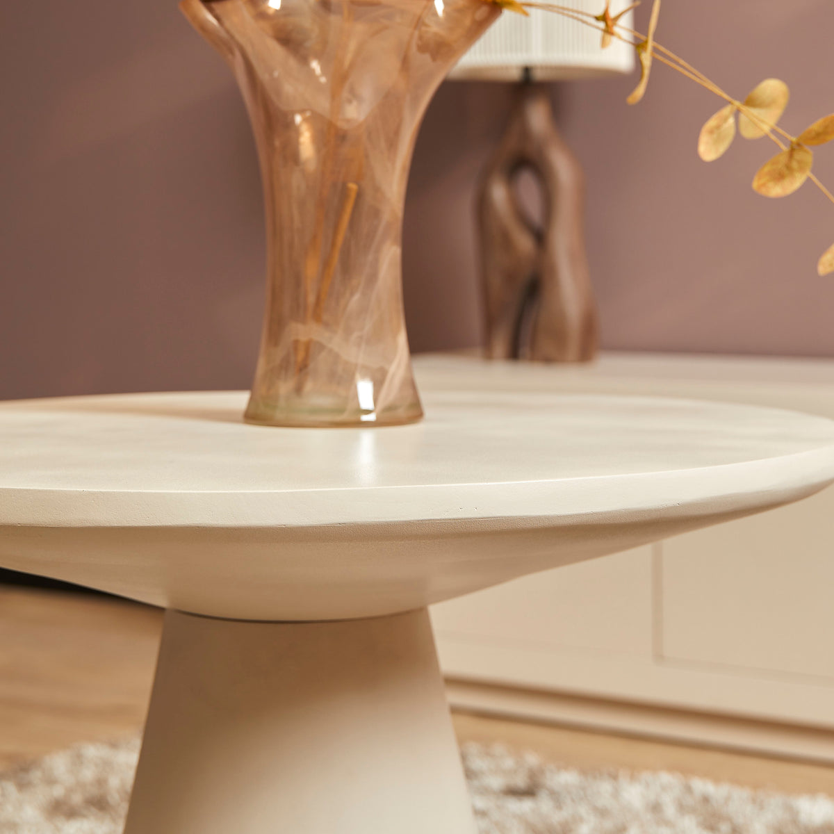 Salontafel met rond wit blad en slanke voet, detail van het bovenblad