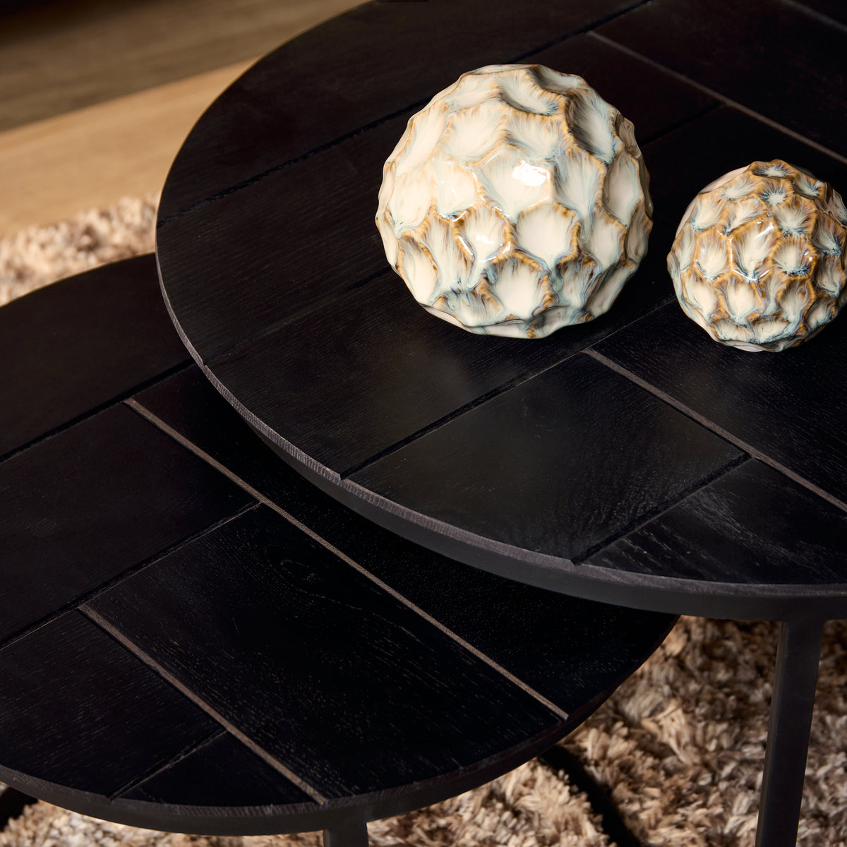 Ronde zwarte salontafel met houten nerf op het blad en zwart frame