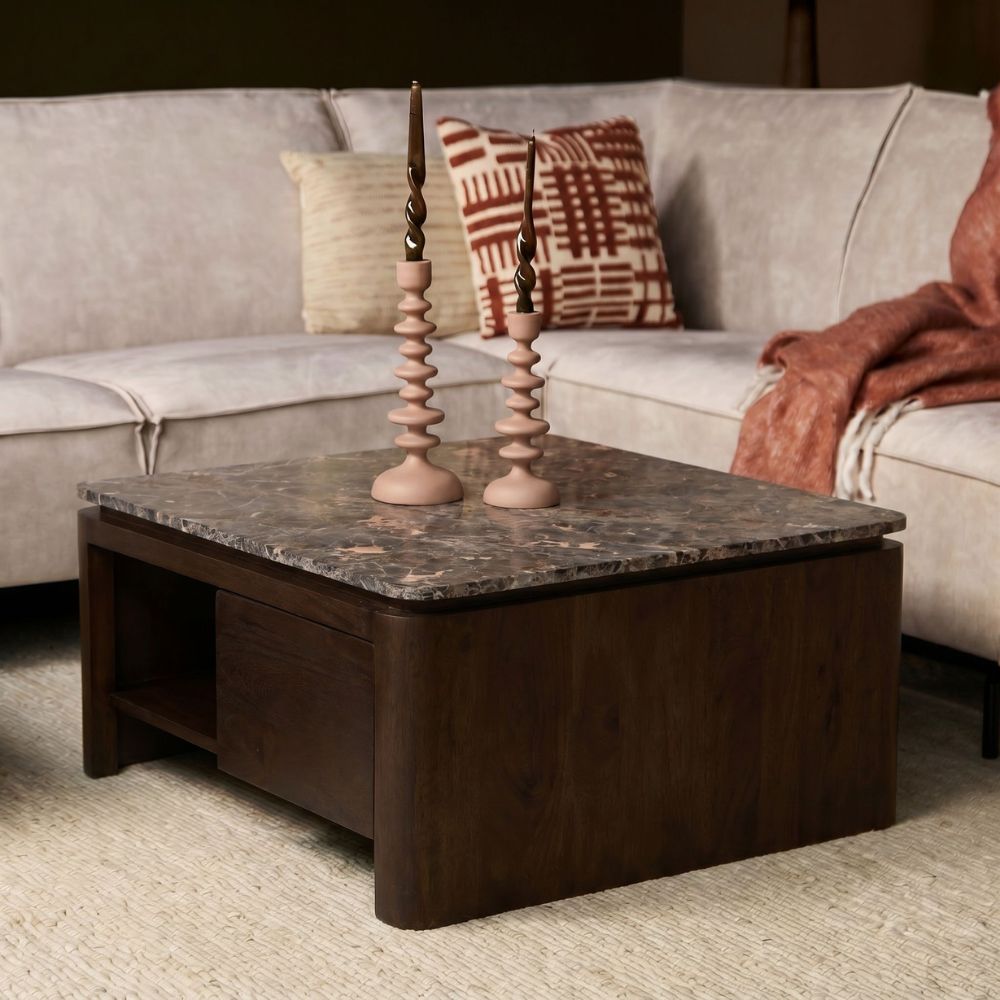 Bruine vierkante salontafel van mangohout met grijs stenen blad en decoratieve kaarsen.