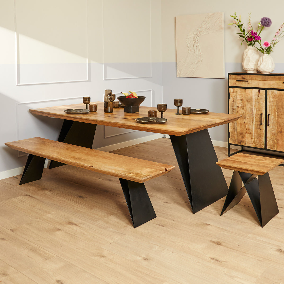 Eetkamertafel met eikenhouten blad en zwarte schuine poten, met houten bankje