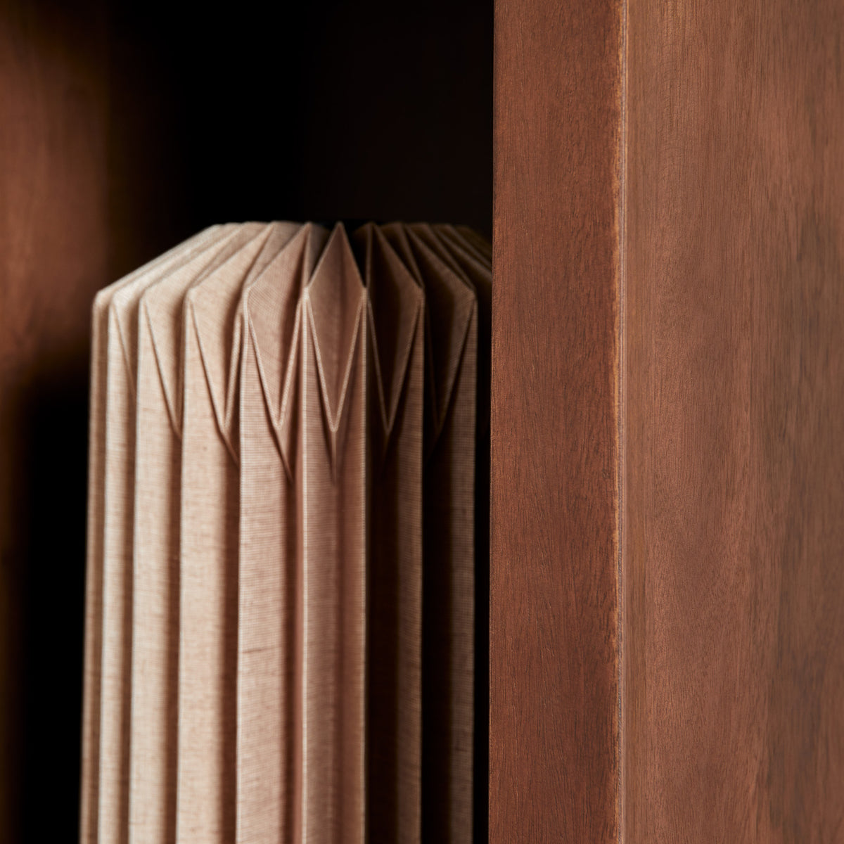 Opbergvak met opgevouwen beige textiel en houten zijwand