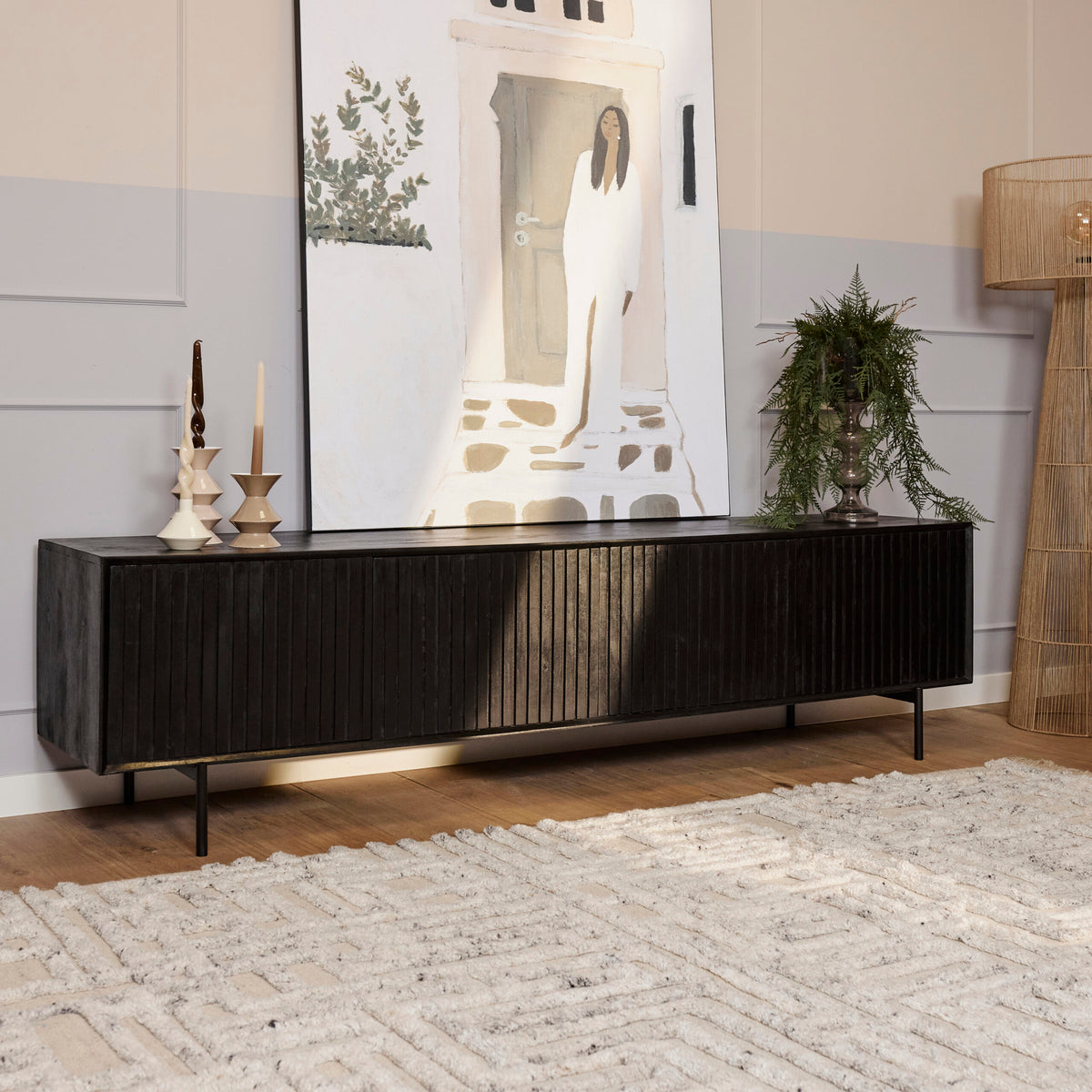 Zwart tv-meubel met geribbelde fronten, lange kast en twee deuren, op smalle poten.