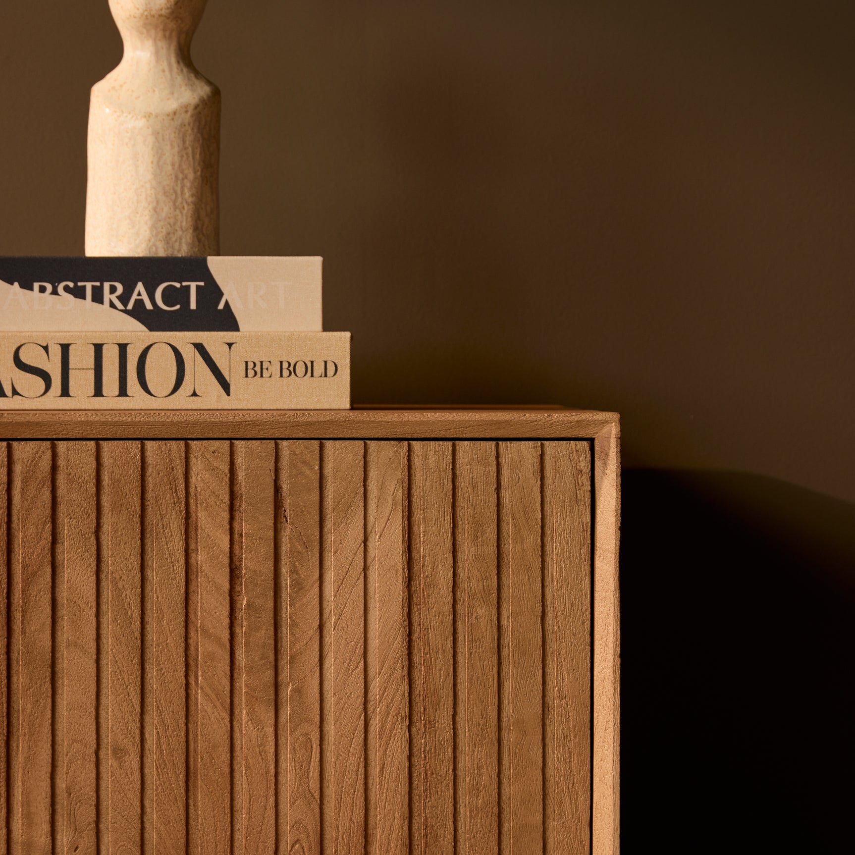 Dressoirfront in naturel hout met verticale groeven en zwarte onderrand.