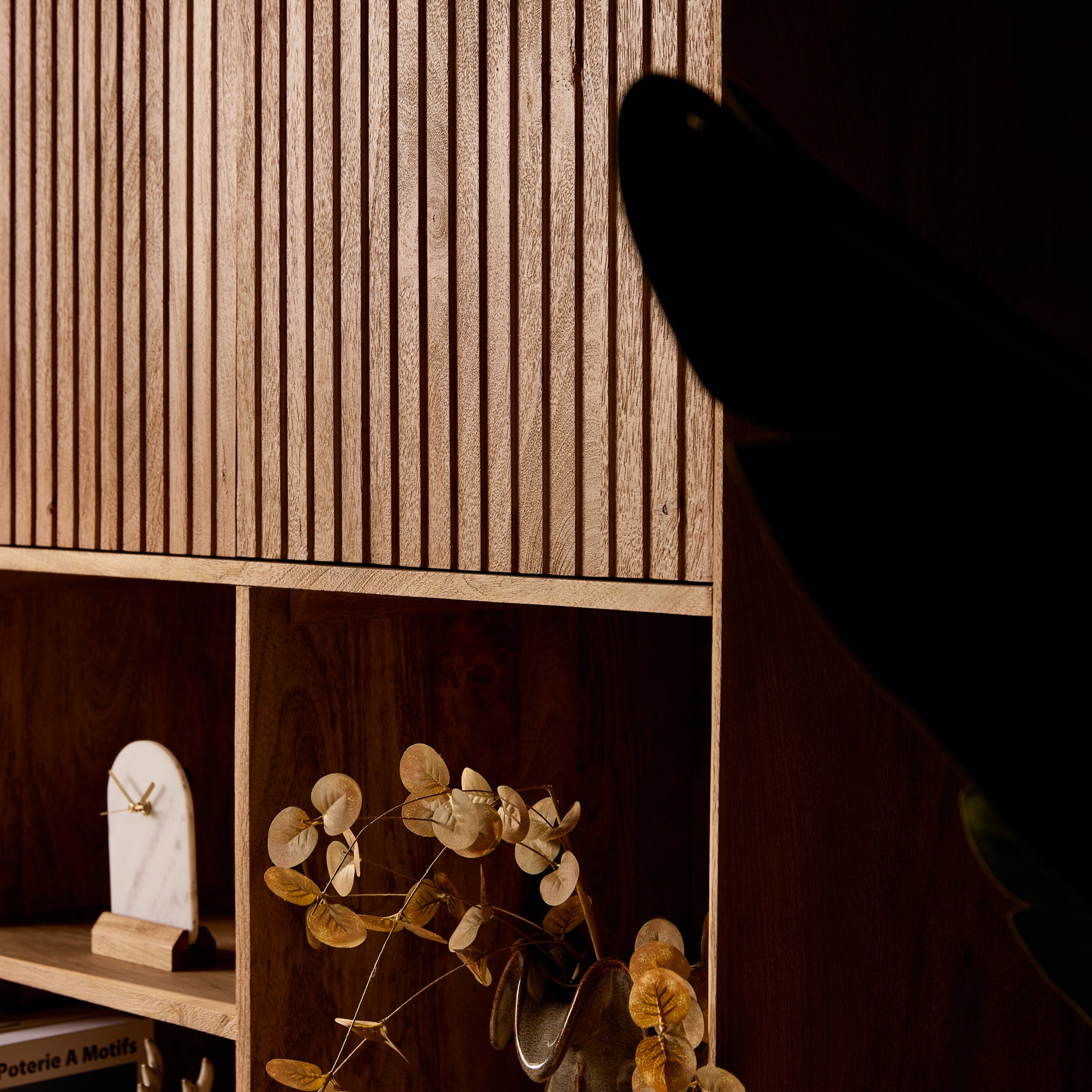 Vakkenkast-detail met open middenvakken en houtnerf; boek en decoratie in de vakken