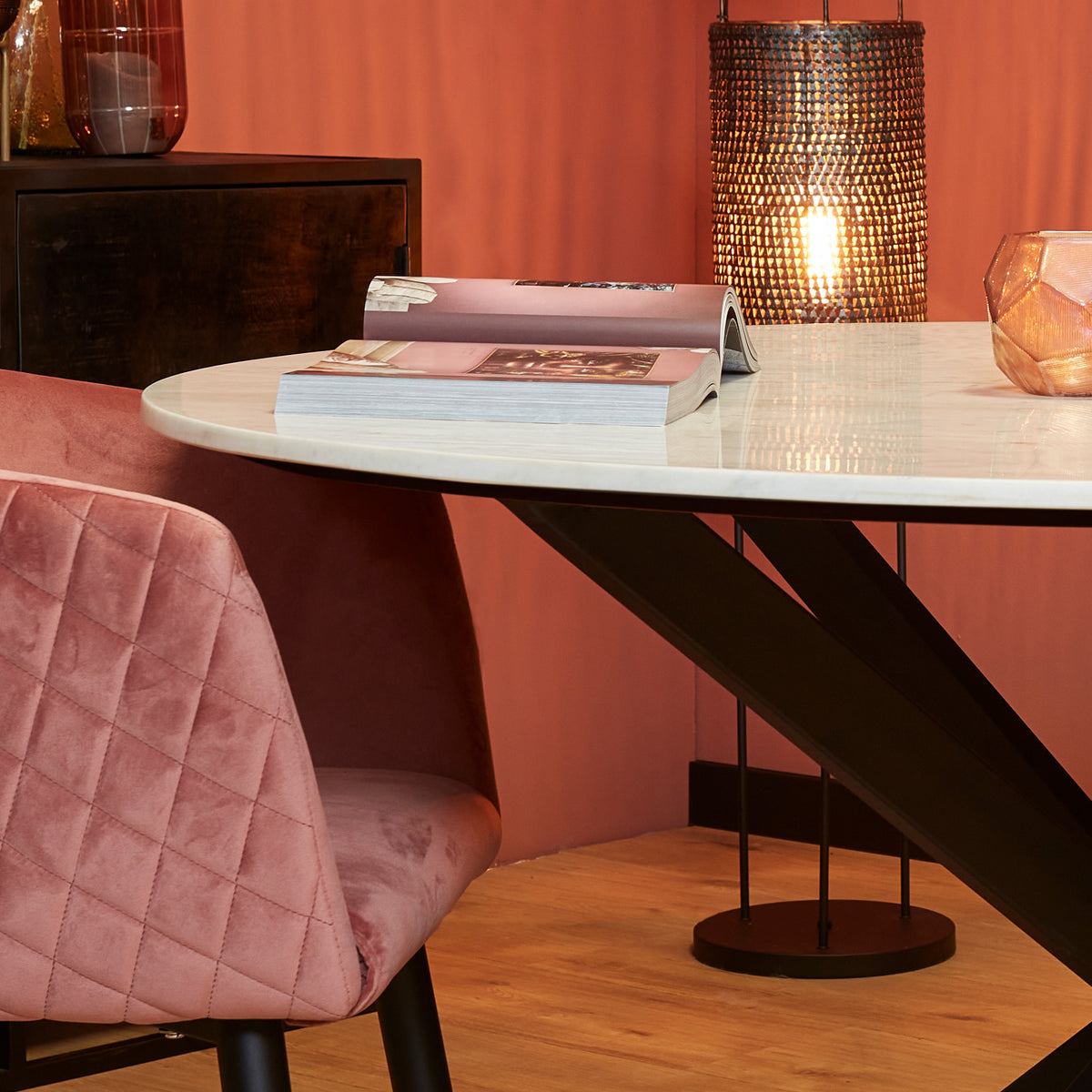Ronde eettafel met wit marmeren blad en zwart diagonaal pootonderstel.