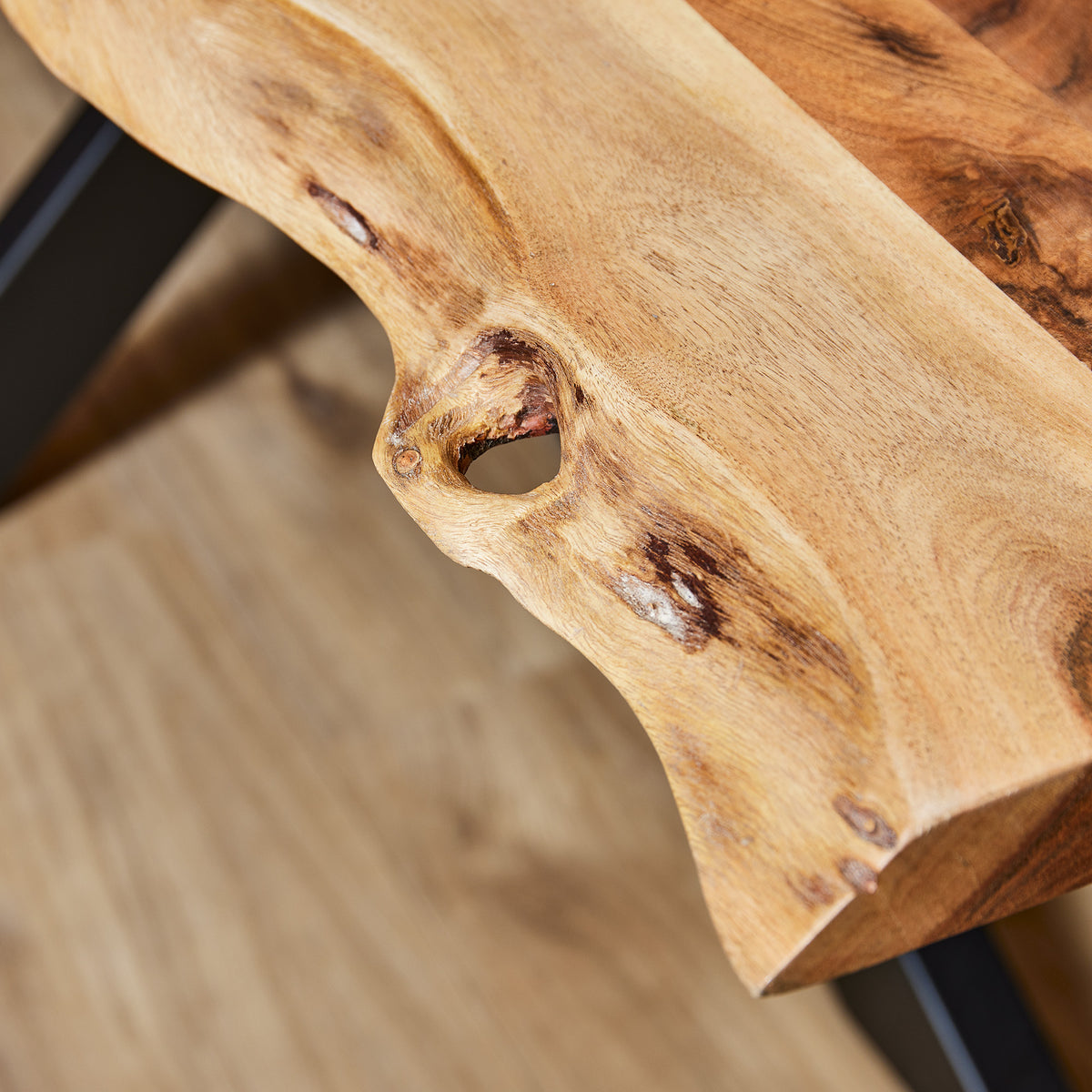 Detail van boomstamtafel: natuurlijke rand met houtnerf en zwarte metalen onderstel
