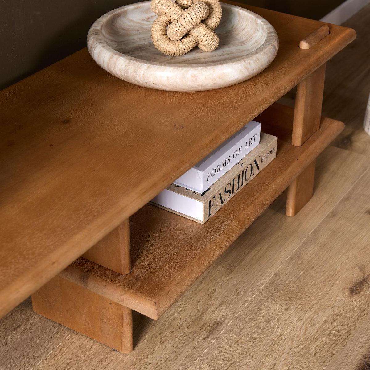 Tv-meubel met open onderplank en boeken op een bruin houten rand, houtnerf zichtbaar