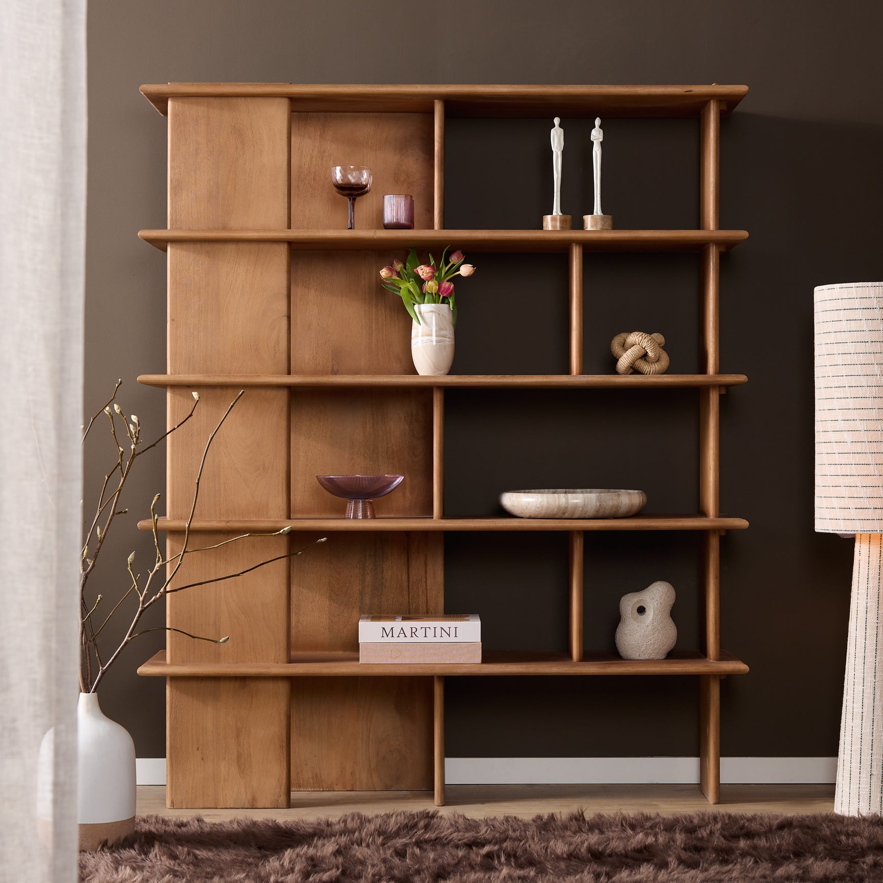 Wandkast met open vakken, gevuld met decoratie zoals bloemen en kaarsen op planken.