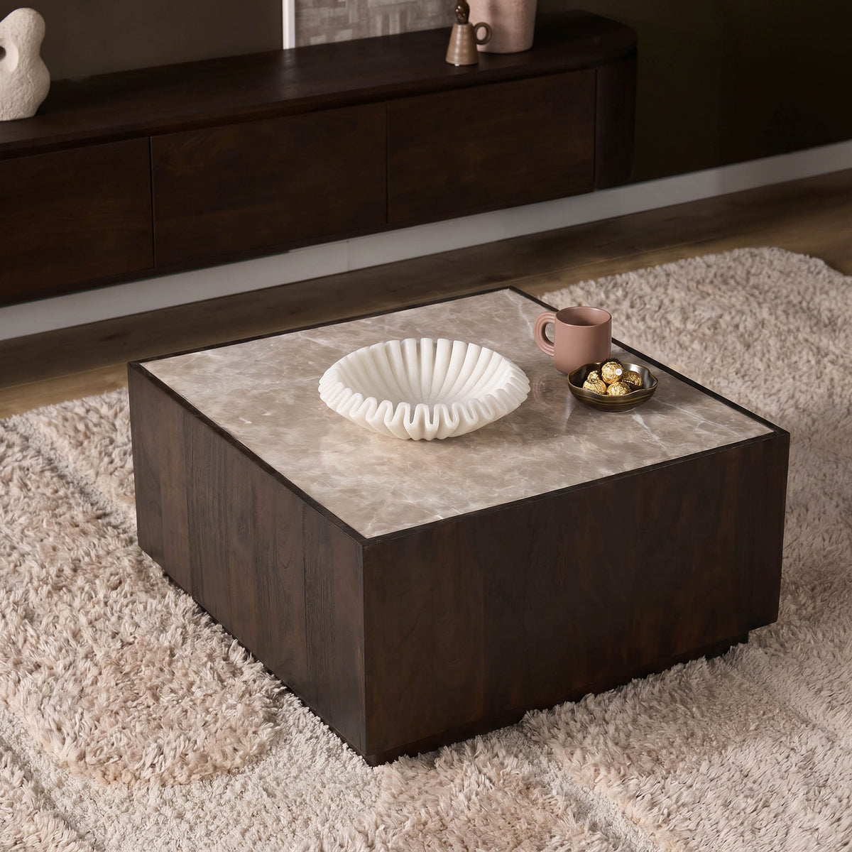 Salontafel op een kleed met beige marmeren blad; donker houten onderstel.