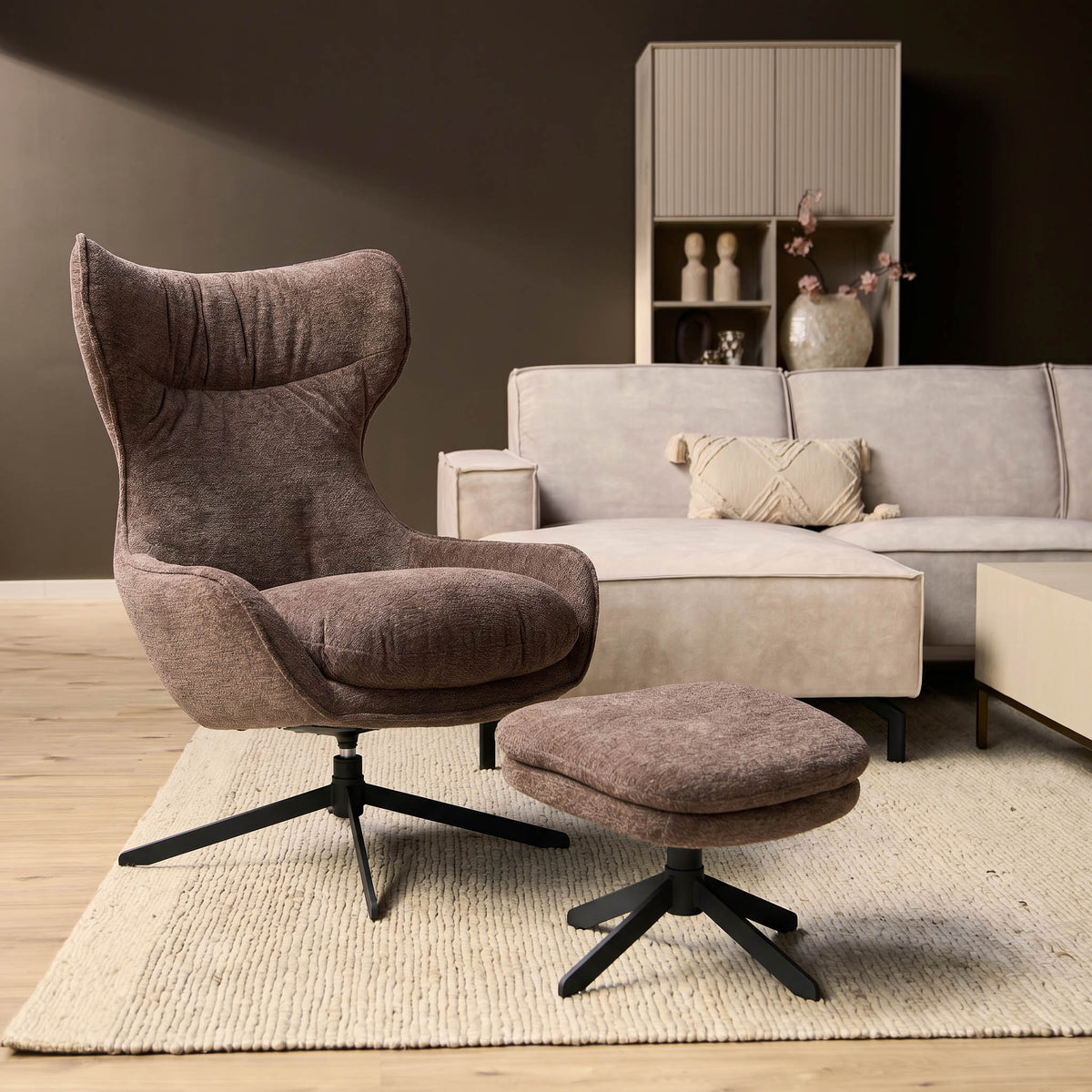 Fauteuil Olivia met draaibare voet en bijpassende poef, donkere stof.