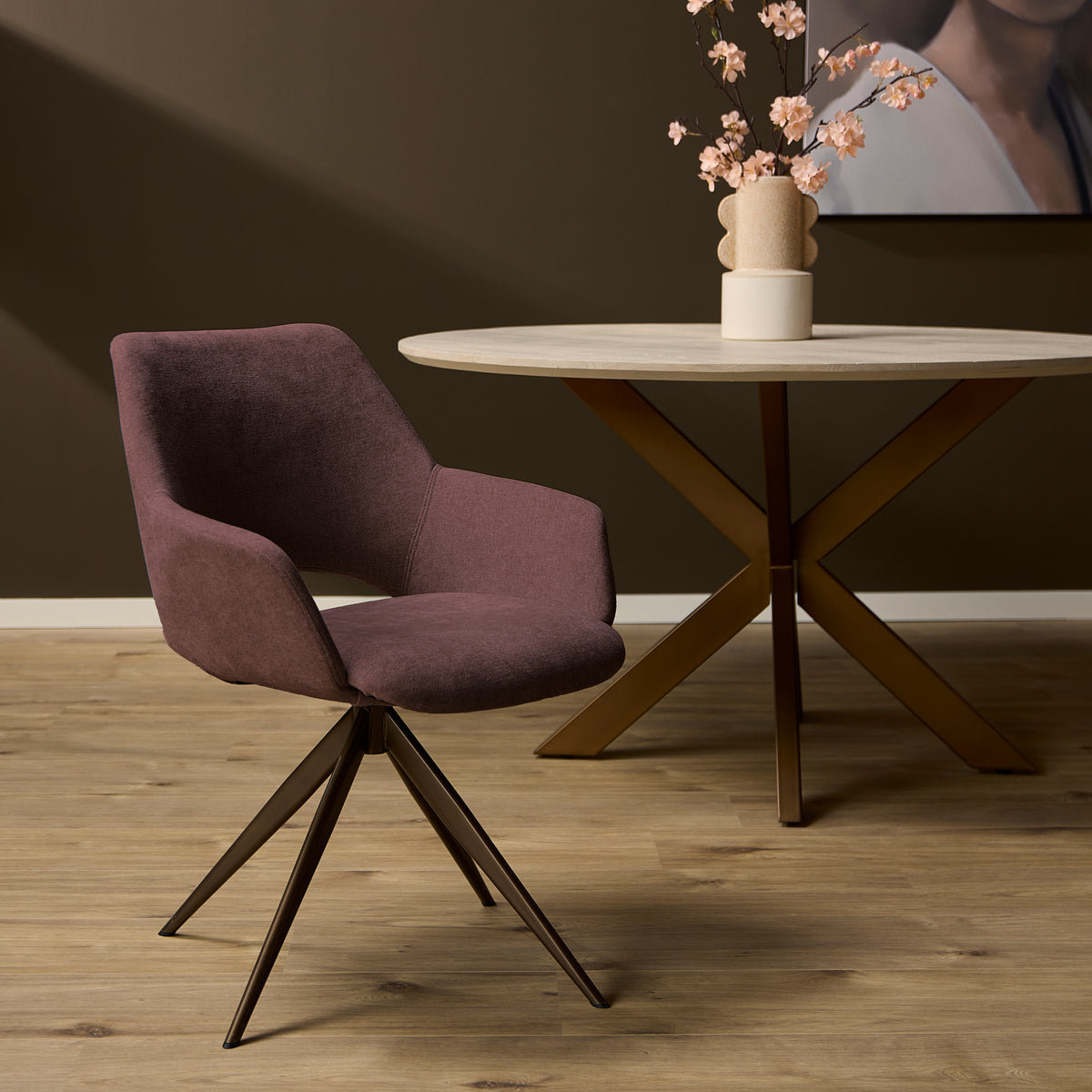 Eetkamerstoel met mauve stoffering, ronde zitting, armleuningen en metalen spinpoot.