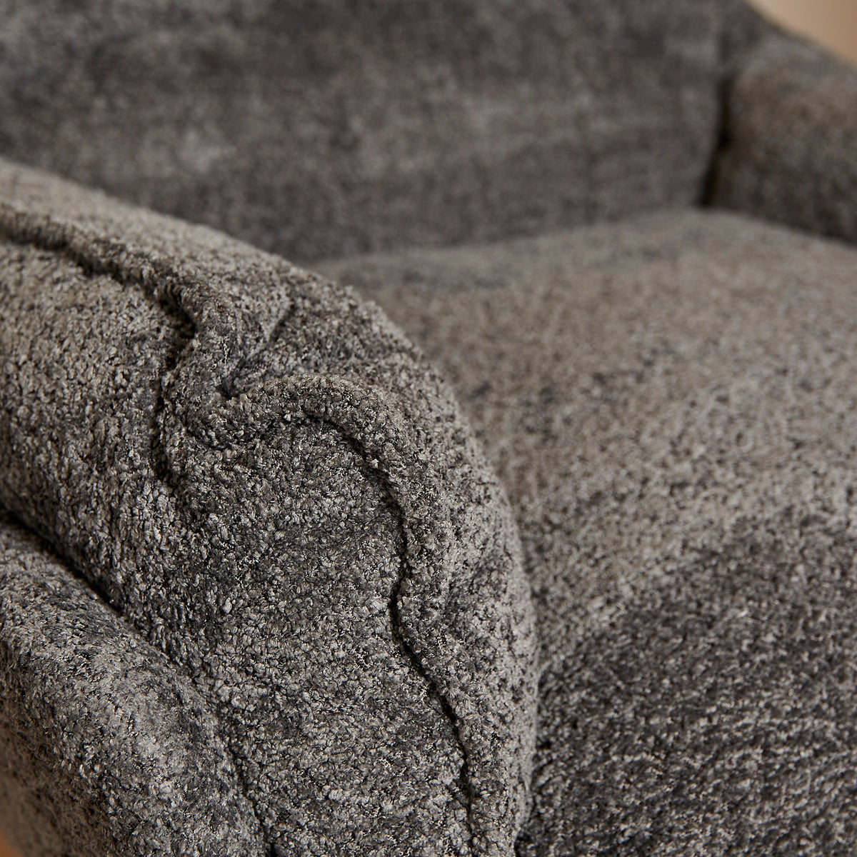 Donkergrijze fauteuil met opgerolde armleuning en gestoffeerde stiksels