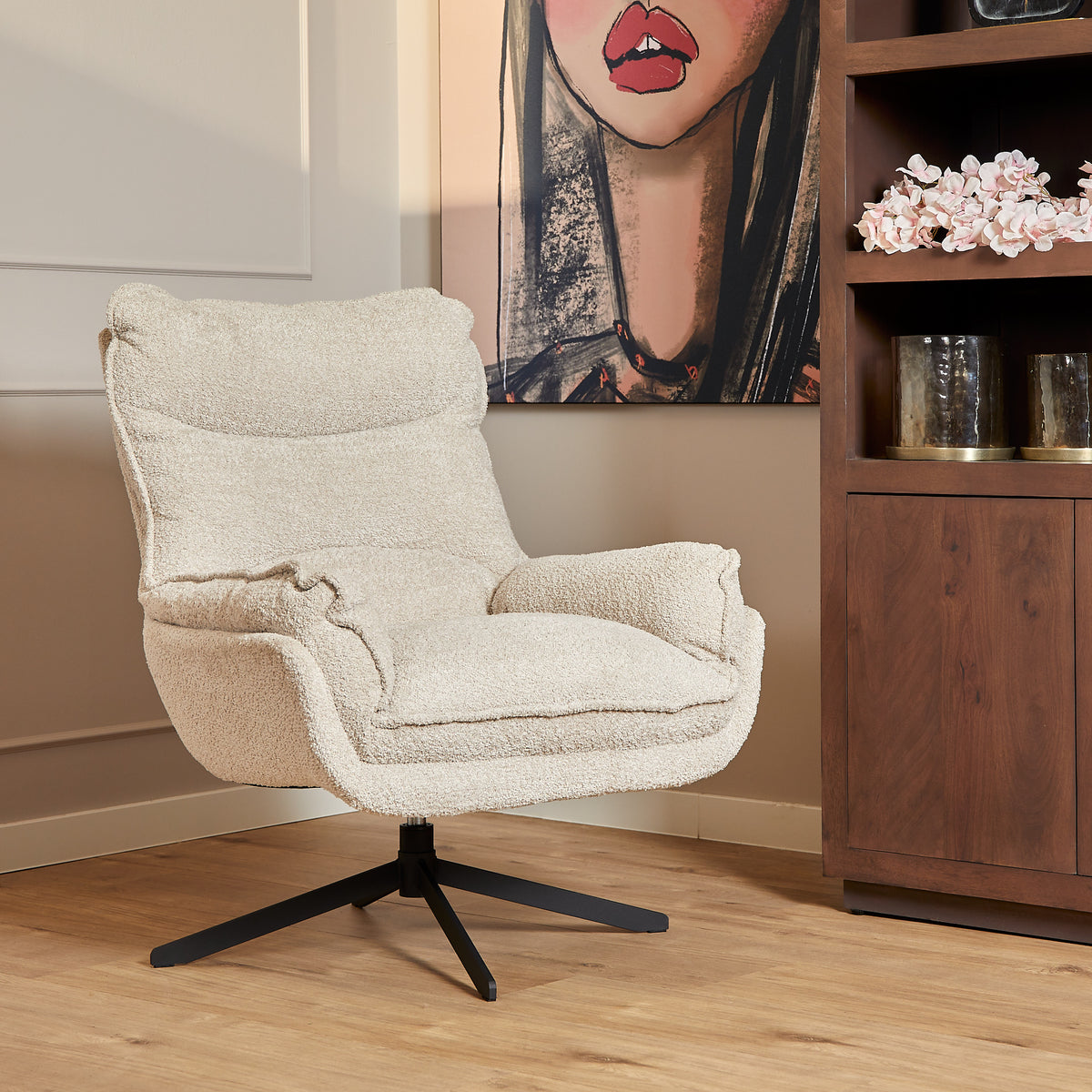 Draaifauteuil met gebroken-witte bouclé bekleding en zwarte stervoet, met open armleuningen.