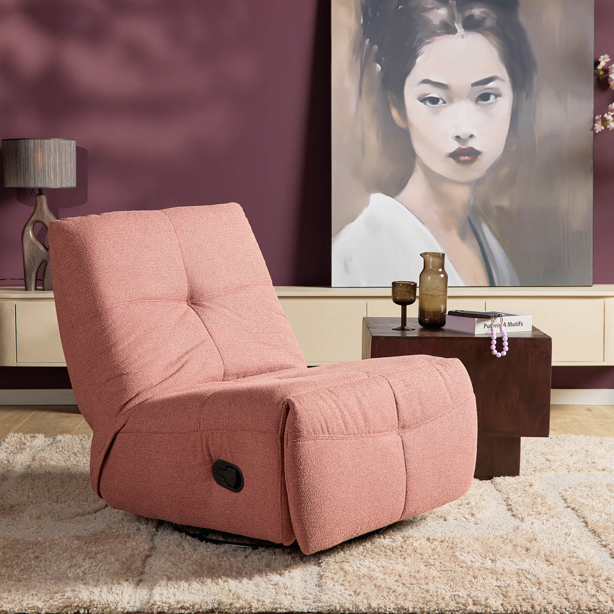 Roze relaxfauteuil met opklapbare voetensteun, ronde zit en armleuningen.