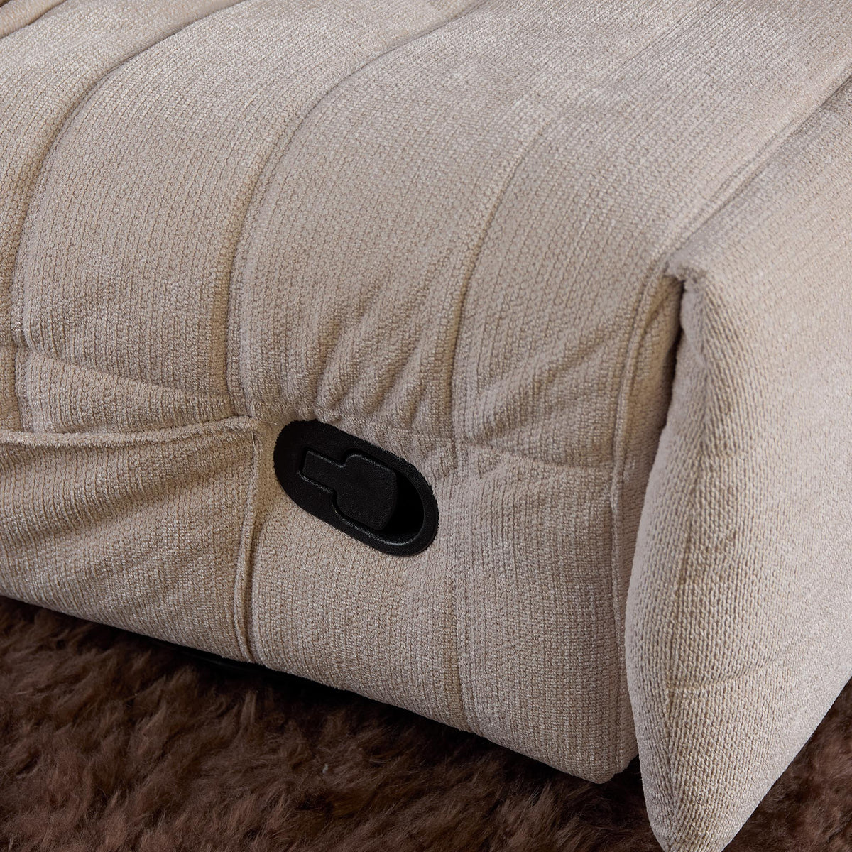 Beige relaxfauteuil met zwarte bedieningsknop en gestikte naden op arm en zijkant