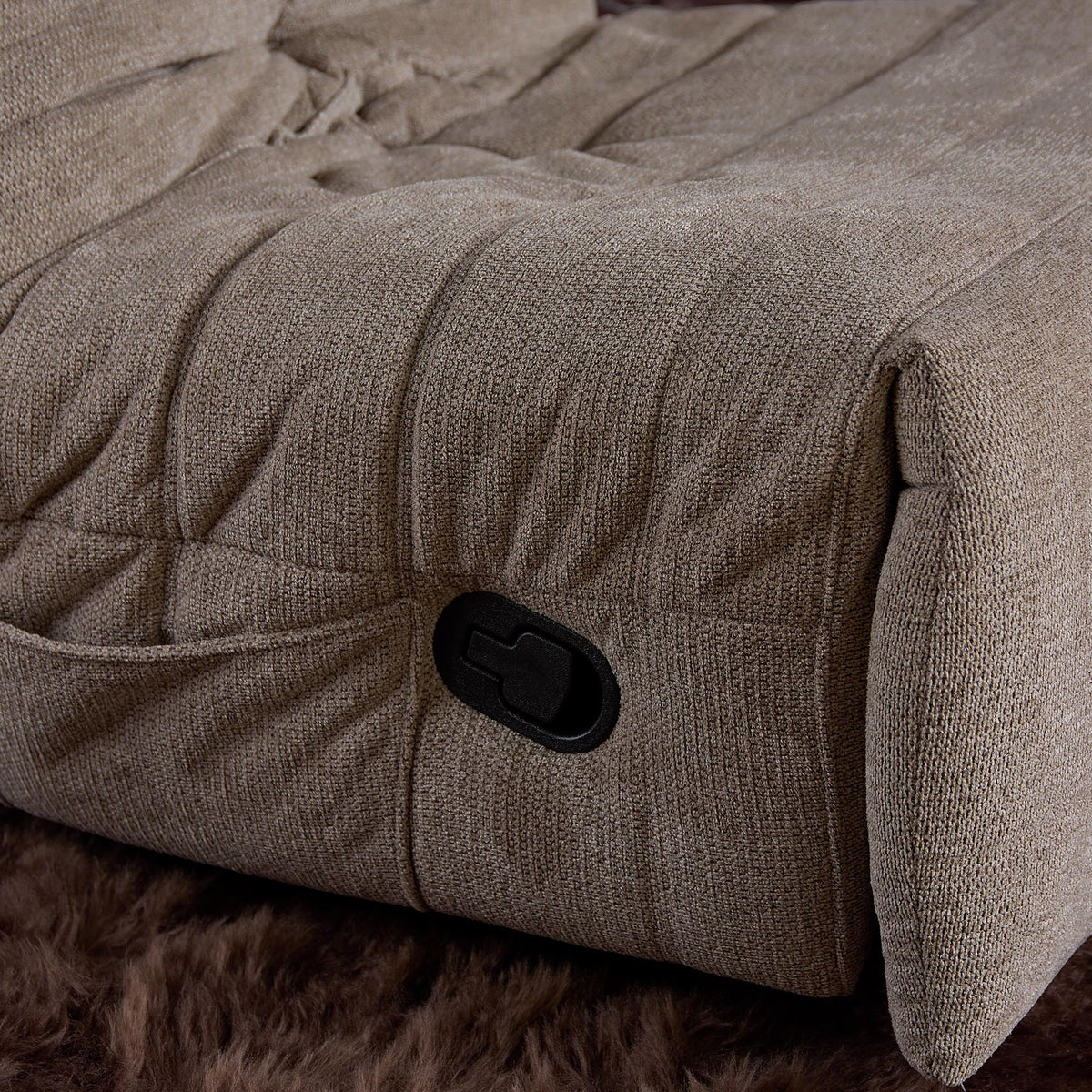 Relaxfauteuil Zen taupe: detail van armsteun met zwarte bedieningsknop en plooien in stof