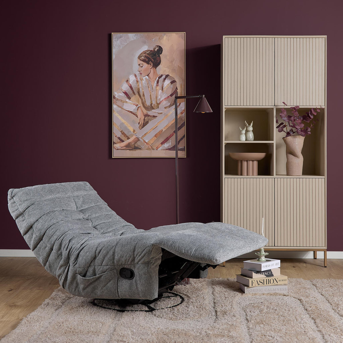 Grijze relaxfauteuil met uitgeschoven voetensteun en gestoffeerde armleuning.