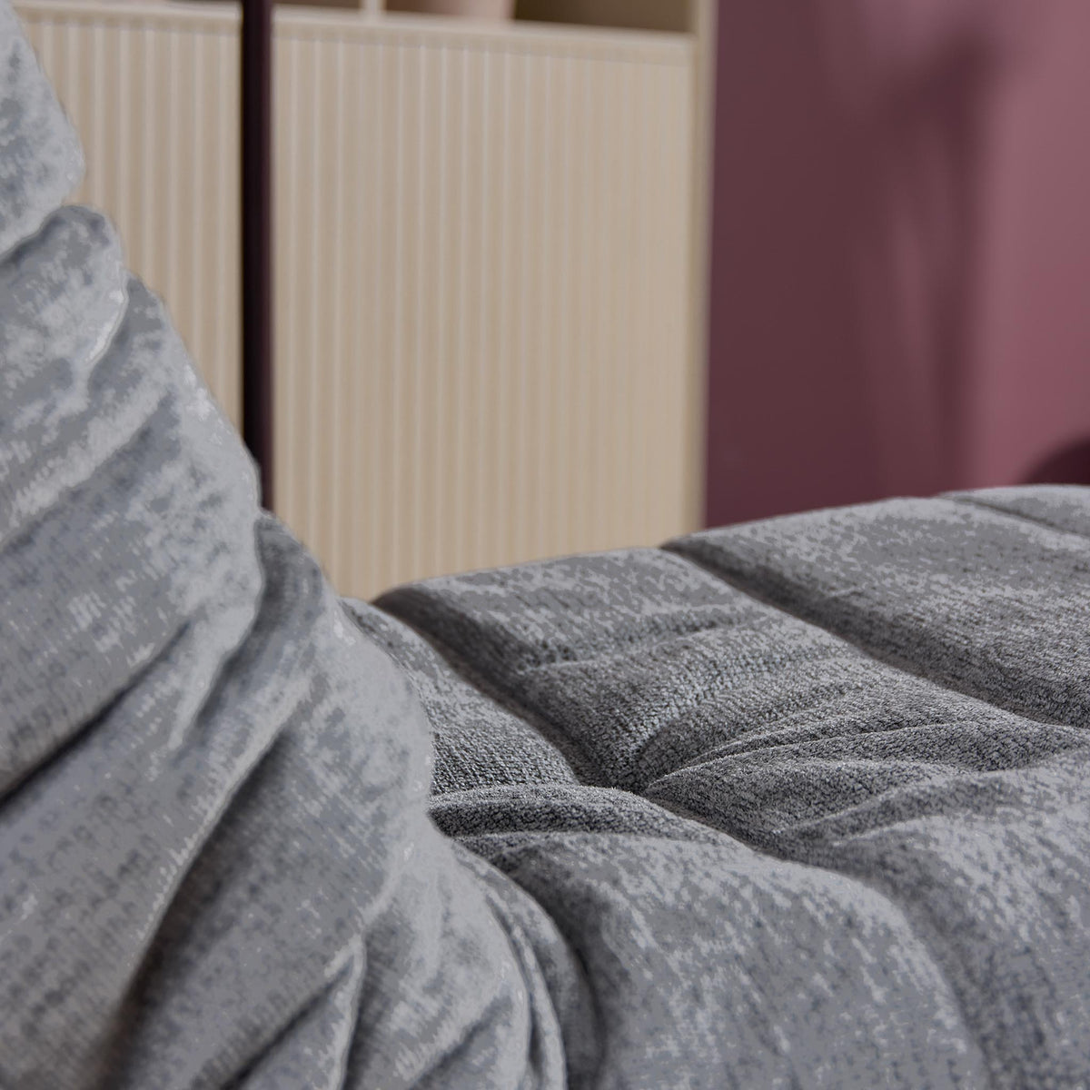 Close-up van grijze bekleding van relaxfauteuil bij de rug en voetensteun.