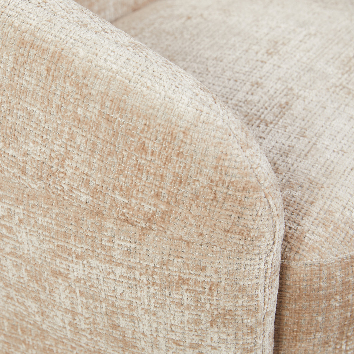 Close-up van beige armleuning en zijkant van de fauteuil, met grove stofstructuur en afgeronde vorm.